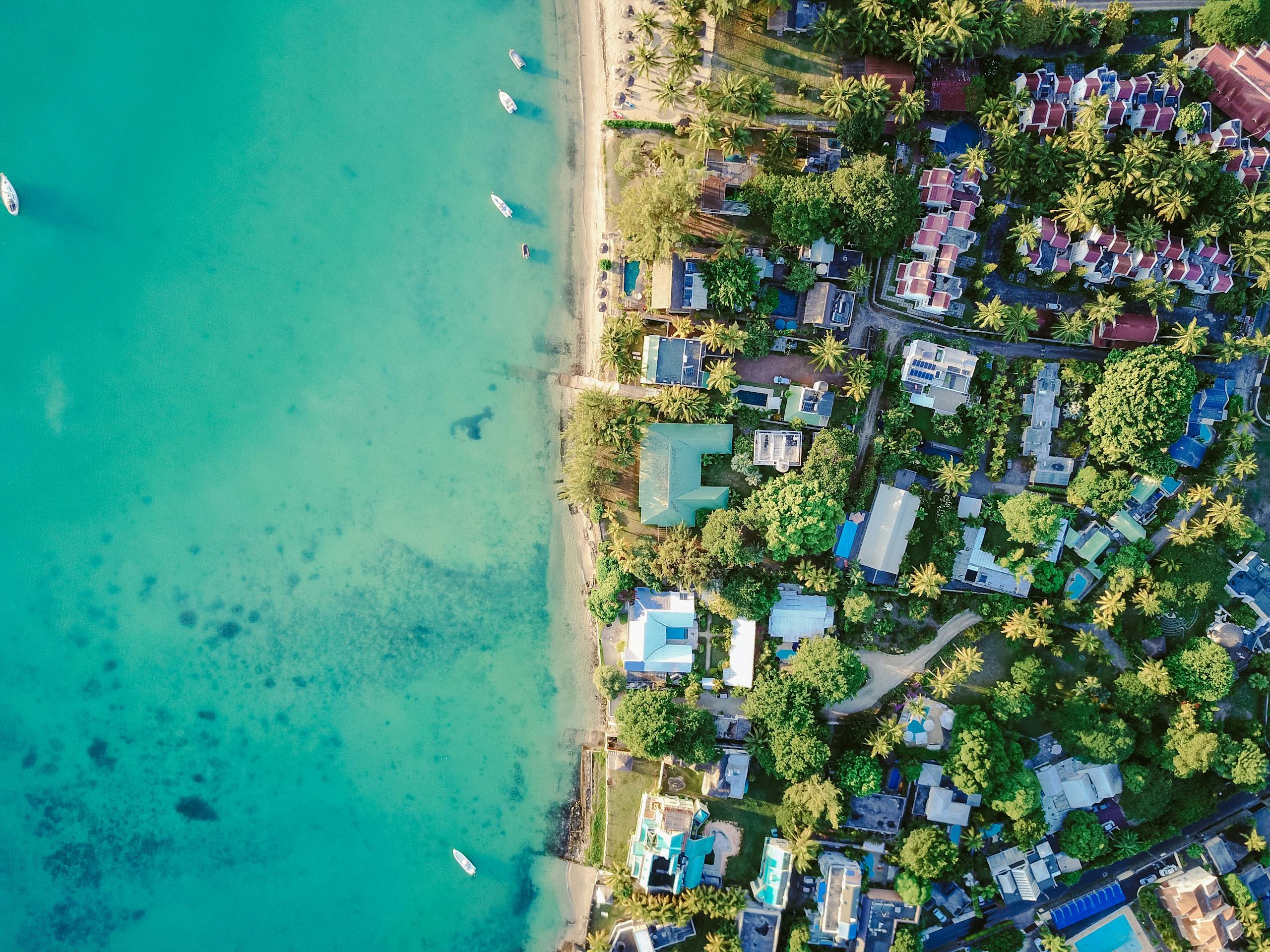 A stunning aerial view of a vibrant tropical coastal village with turquoise waters and lush greenery.